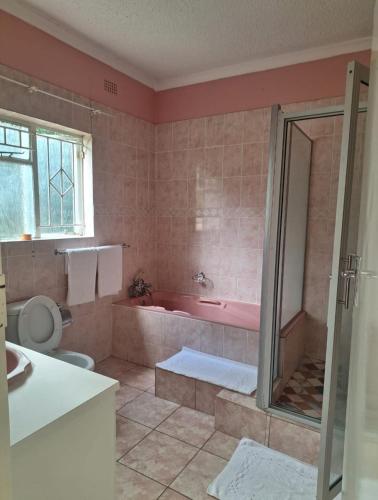 a bathroom with a tub and a toilet and a sink at Eastview Guest House in Harare