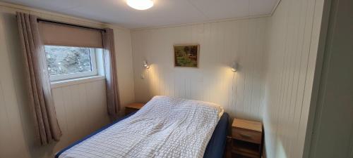 a small bedroom with a bed and a window at Apartment Solbakken Feriehus in Fevåg
