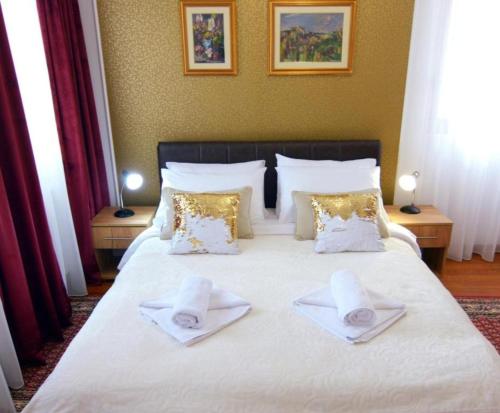 a bedroom with a large white bed with towels on it at Apolon Spa in Vrnjačka Banja