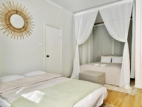 a white bedroom with two beds and a mirror at 1BR Demure Design & Urban Living in Kamppi in Helsinki
