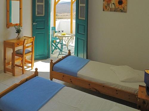 two beds in a room with a table and a table at Irene Rooms in Chora Folegandros
