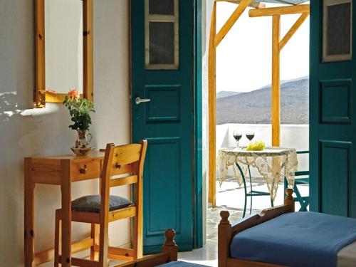 a room with a blue door and a table with a tableearcher at Irene Rooms in Chora Folegandros