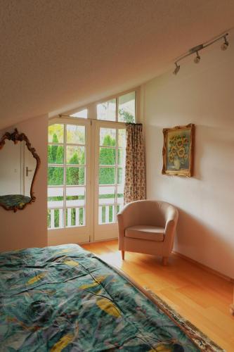 a bedroom with a bed and a chair and a window at Ferienwohnung de Best inkl. Chiemgaukarte in Siegsdorf