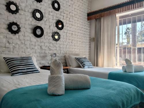 a room with two beds and a wall with clocks at Gorgeous Gecko Guesthouse in Modimolle