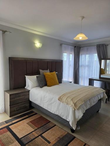 a bedroom with a large bed with yellow pillows at Ivory & Mane Estate - Jacaranda in Harare