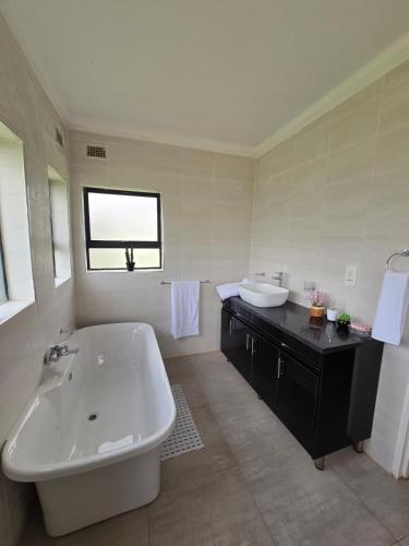 a white bathroom with a tub and a sink at Ivory & Mane Estate - Jacaranda in Harare