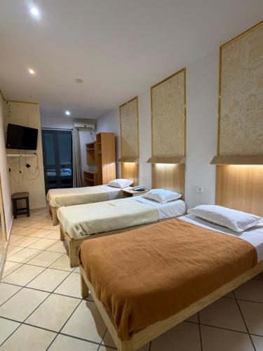 a hotel room with three beds and a television at Hotel Roma in Tunis