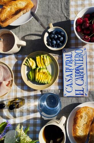 a table topped with plates of food and bowls of fruit at El Carpintero in Trevélez