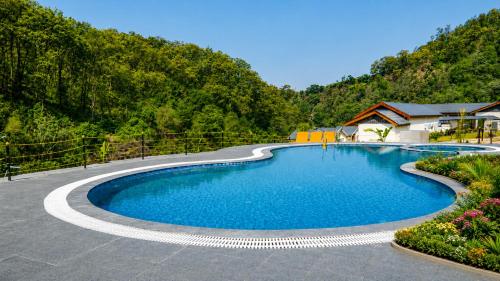 a swimming pool in the middle of a mountain at The JJ Corbett Bliss, Sitabani A River Access Wildlife Resort in Amgarhi