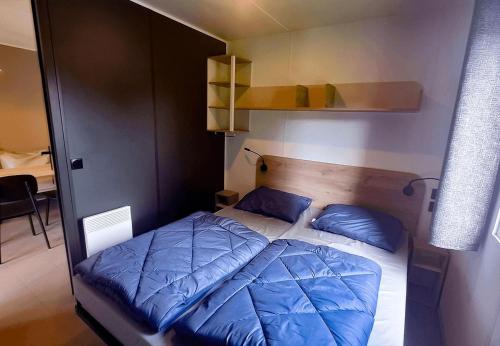 a bed with blue pillows in a small room at Camp Diekirch - Mobilehome Plus 4p in Gilsdorf