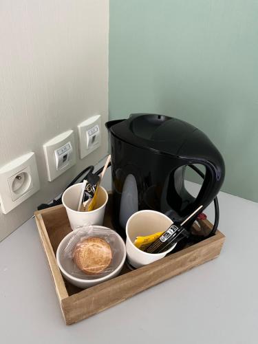 a black tea kettle and bowls on a wooden tray at Hôtel des Voyageurs in Changé