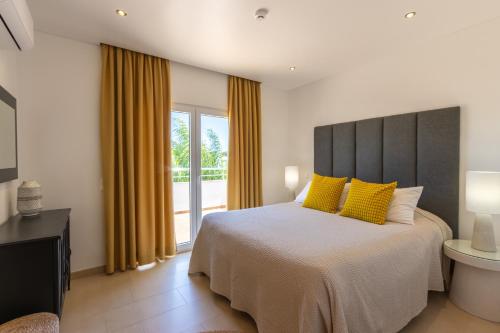 a bedroom with a large bed with yellow pillows at Pine Tree Seaside Apartments 500m to Beach in Albufeira