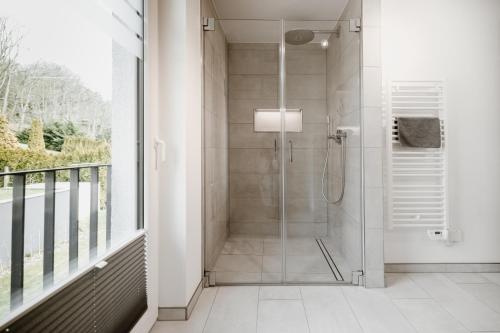 a bathroom with a shower with a glass door at FourElements Grand Chalet in Blankenburg