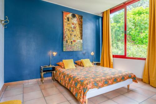 a blue bedroom with a bed and a window at Le Clos Des Chênes in Lagarde-Paréol
