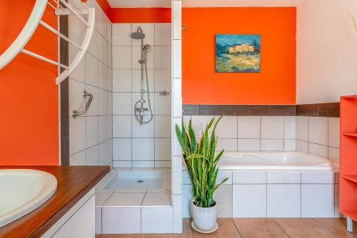 an orange bathroom with a tub and a plant at Le Clos Des Chênes in Lagarde-Paréol