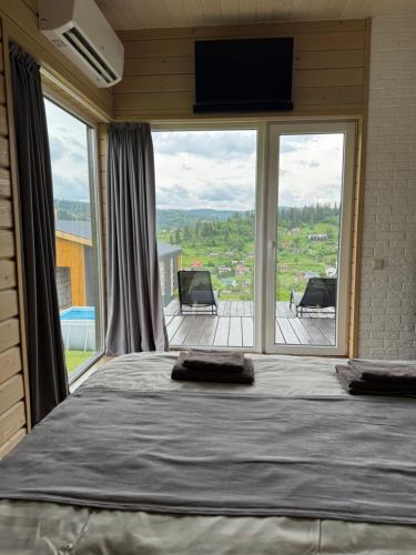 a bedroom with a large bed and a large window at DIDO house in Slavske