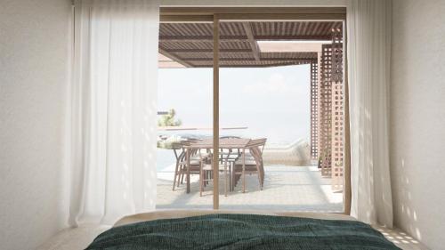 a bedroom with a view of a table and a balcony at Thalasses in Adelianos Kampos