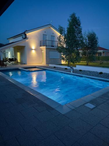 a swimming pool in front of a house at night at Kuća za odmor Nina in Čapljina