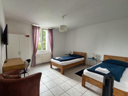 a bedroom with two beds and a desk and a chair at Casa Carmela in Solothurn