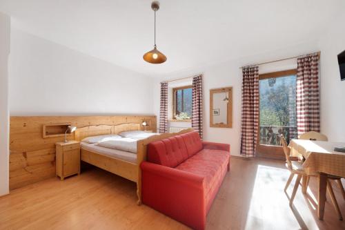 a bedroom with a bed and a red couch at Mayrhof Zimmer, Bauernhofurlaub in San Pancrazio dʼUltimo