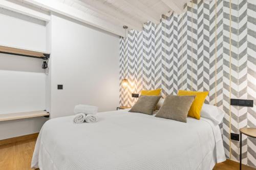 a bedroom with a large white bed with yellow pillows at Apartamentos el Caneyón in San Juan de Parres