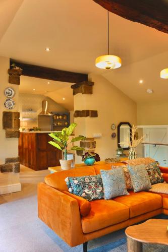 a living room with an orange couch in a room at Town Gate Cottage in Stainland