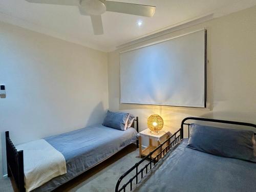 a bedroom with two beds and a large screen at 3BR Retreat with Sunset Views over Brisbane Water in Green Point