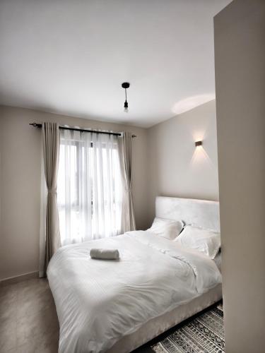 a bedroom with a white bed with a window at Chic One Bedroom Apartment near The Kenya School of Government - KSG in Nairobi