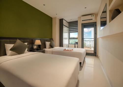 a hotel room with two beds and a window at Jolia Nha Trang Hotel in Nha Trang