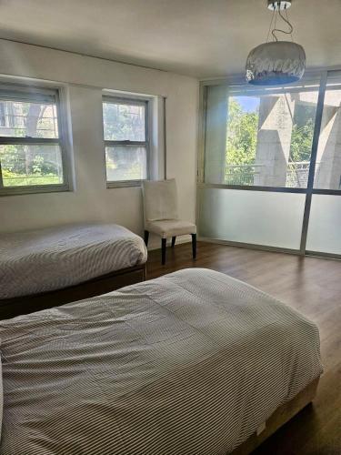 a bedroom with two beds and a chair and windows at Kosher Villa in earth of Moshava in Jerusalem