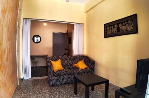 a living room with a couch with two orange pillows at Amelie in Loutraki