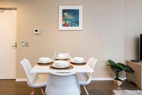 a white dining room with a white table and chairs at Darwin Waterfront Luxury Suites in Darwin