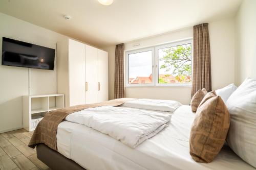 a bedroom with a large white bed and a window at Möwe - Apartment in der Hafenresidenz mit Balkon & Wellness in Waren