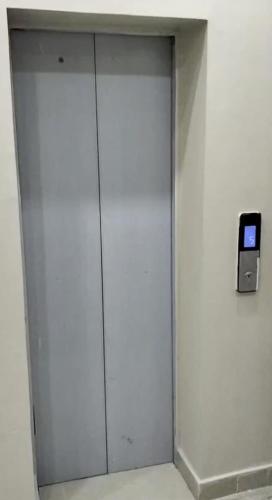 a white elevator with a cell phone on a wall at Shabbir Premier Heights in Lahore
