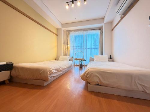 two beds in a room with a window at ura 東横のヨコ301 in Kaigandōri