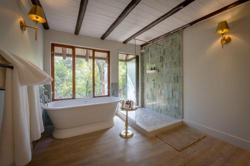 a large bathroom with a tub and a window at Shimungwe Lodge, Thornybush Game Reserve in Hoedspruit