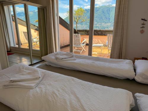 two beds in a room with a view of a balcony at Orizzonte Blu by HolAp SA in Gambarogno