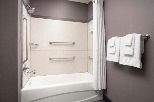 a bathroom with a tub and a shower with towels at Courtyard by Marriott Valdosta in Valdosta