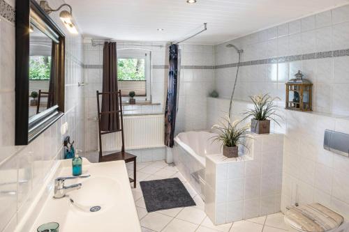 a white bathroom with a tub and a sink and a bath tub at Ferienwohnung An der Wublitz in Leest