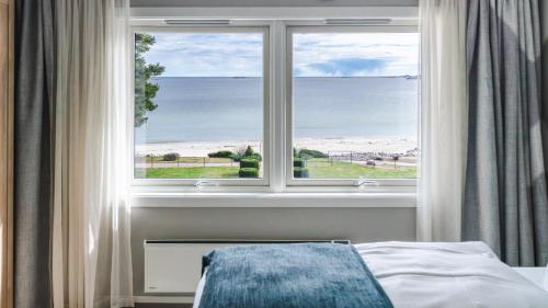 a bedroom with a window with a view of the ocean at Strand Hotel Fevik - by Classic Norway Hotels in Grimstad