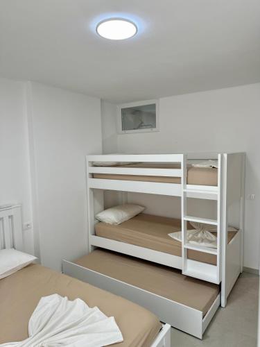 a room with a white bunk bed and a white shelf at SunSis Apartment in Shëngjin