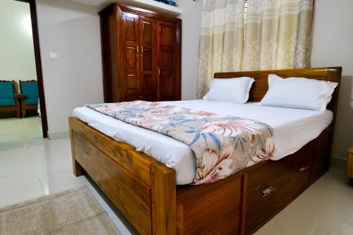 a bedroom with a bed with a wooden bed frame at Aranya Ocean Breeze in Mangalore