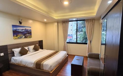 a bedroom with a bed and a chair and a window at Yangchen Home Hotel in Kathmandu