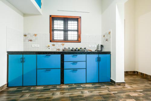 a kitchen with blue cabinets and a window at Aranya Ocean Breeze in Mangalore