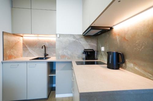 a kitchen with white cabinets and a sink at Apartbaltic- Ventus Park 5 in Świnoujście