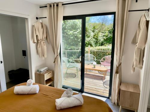 a bedroom with a bed and a balcony with a patio at Maison des Chênes 64 - Spa Lodge in Boucau