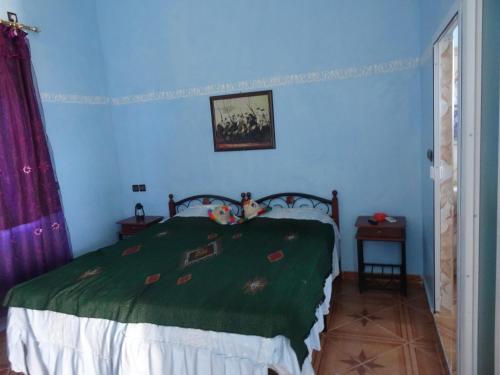 a bedroom with a bed with a green blanket at Tahla Garden in Tahla