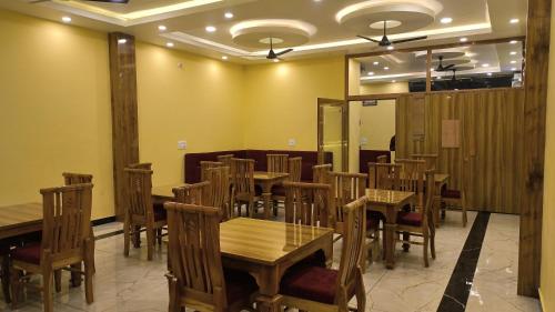a dining room with wooden tables and chairs at Hill Mountain Hotel in Chakarpur