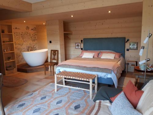 a bedroom with a large bed and a bath tub at Le chalet du Chardonneret in Soultzbach-les-Bains
