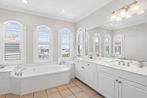 a white bathroom with a tub and two sinks and windows at The Blue Lagoon in Rosemary Beach